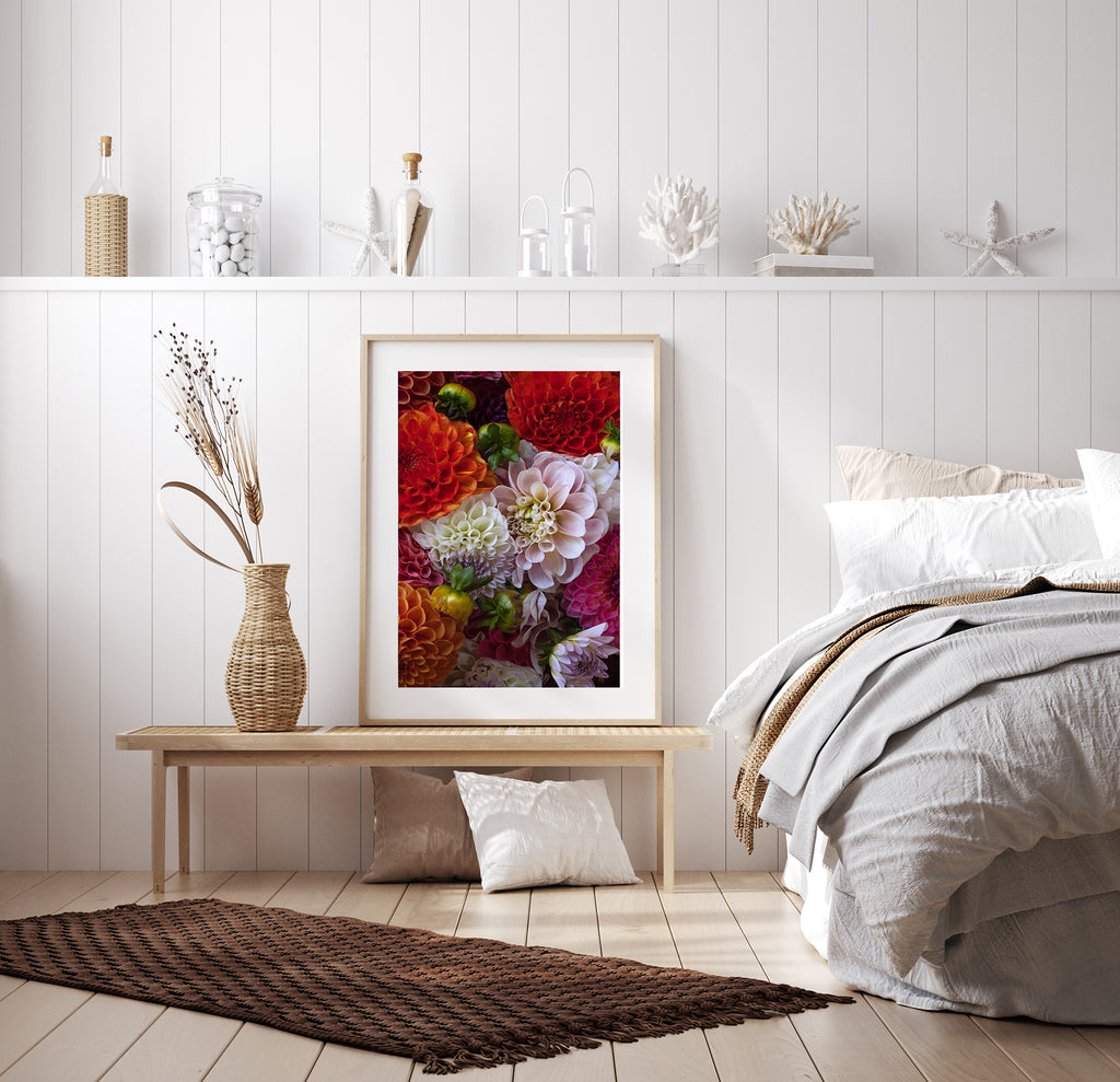 Decorative floral arrangement in a frame on a wooden bench next to a bed with pillows.