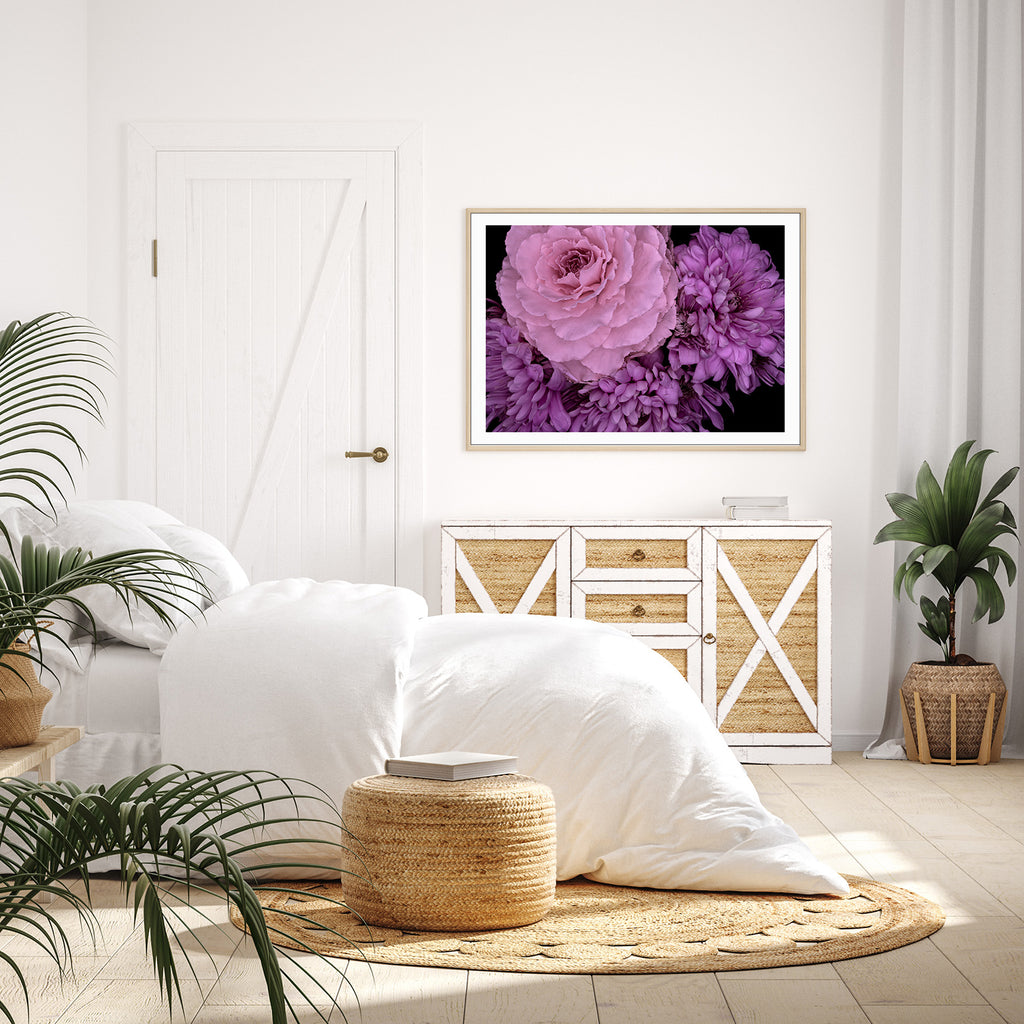 Living room with white sofa, woven ottoman, and framed floral art on wall.