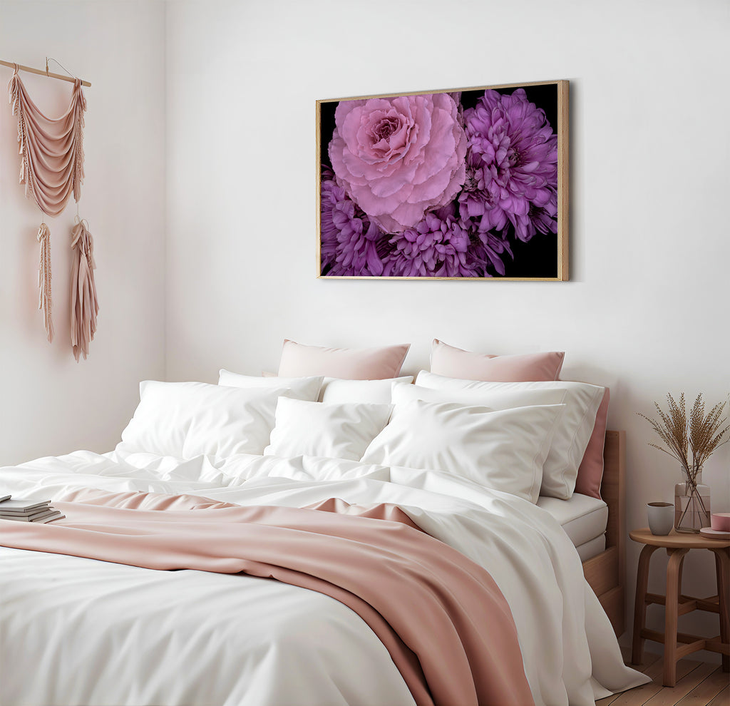 Bedroom with a bed featuring white bedding and pink accents, a floral painting on the wall, and a side table with decorative items.