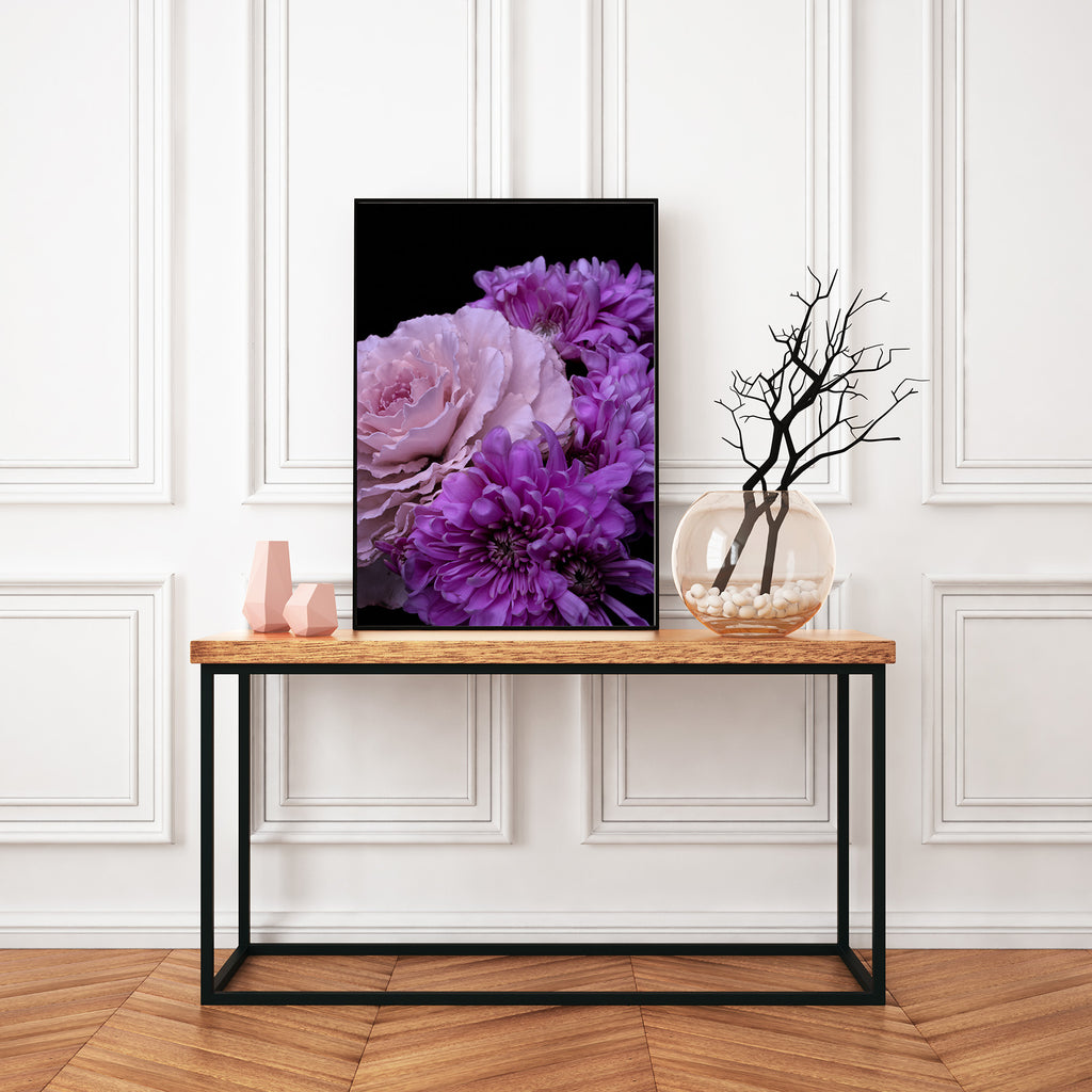 Decorative table with a framed floral print and decorative items against a white paneled wall.