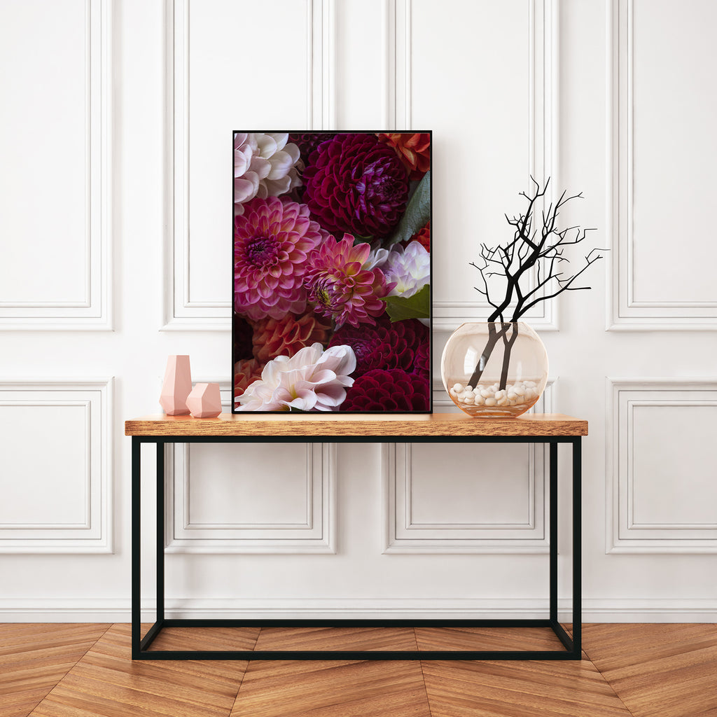 Floral artwork on a wooden console table against a white wall.